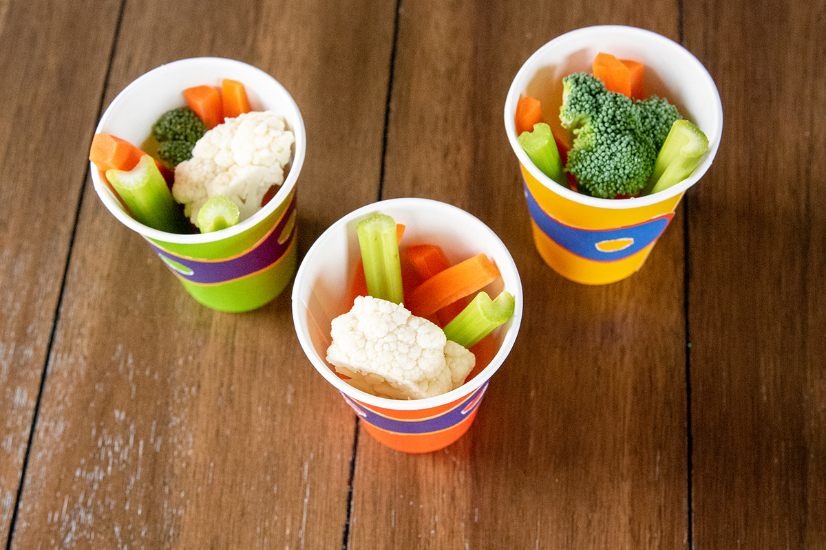 Paper cups containing fresh vegetables to serve as snacks.