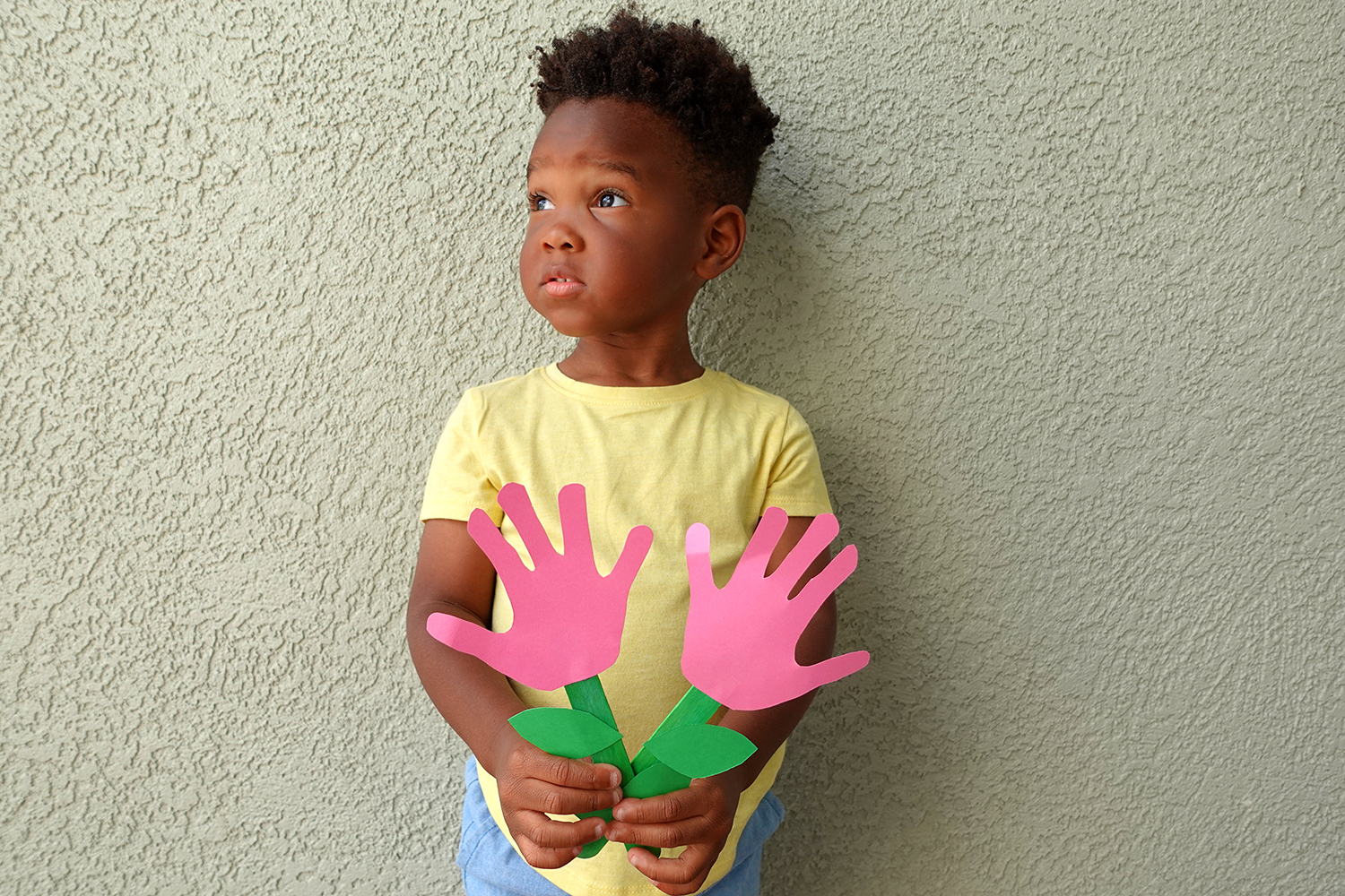 Young child holding handprint flowers craft.