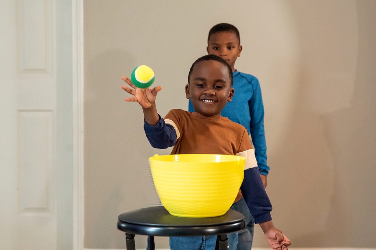 Two children throwing a ball into a bucket in a game of Acorn ball.