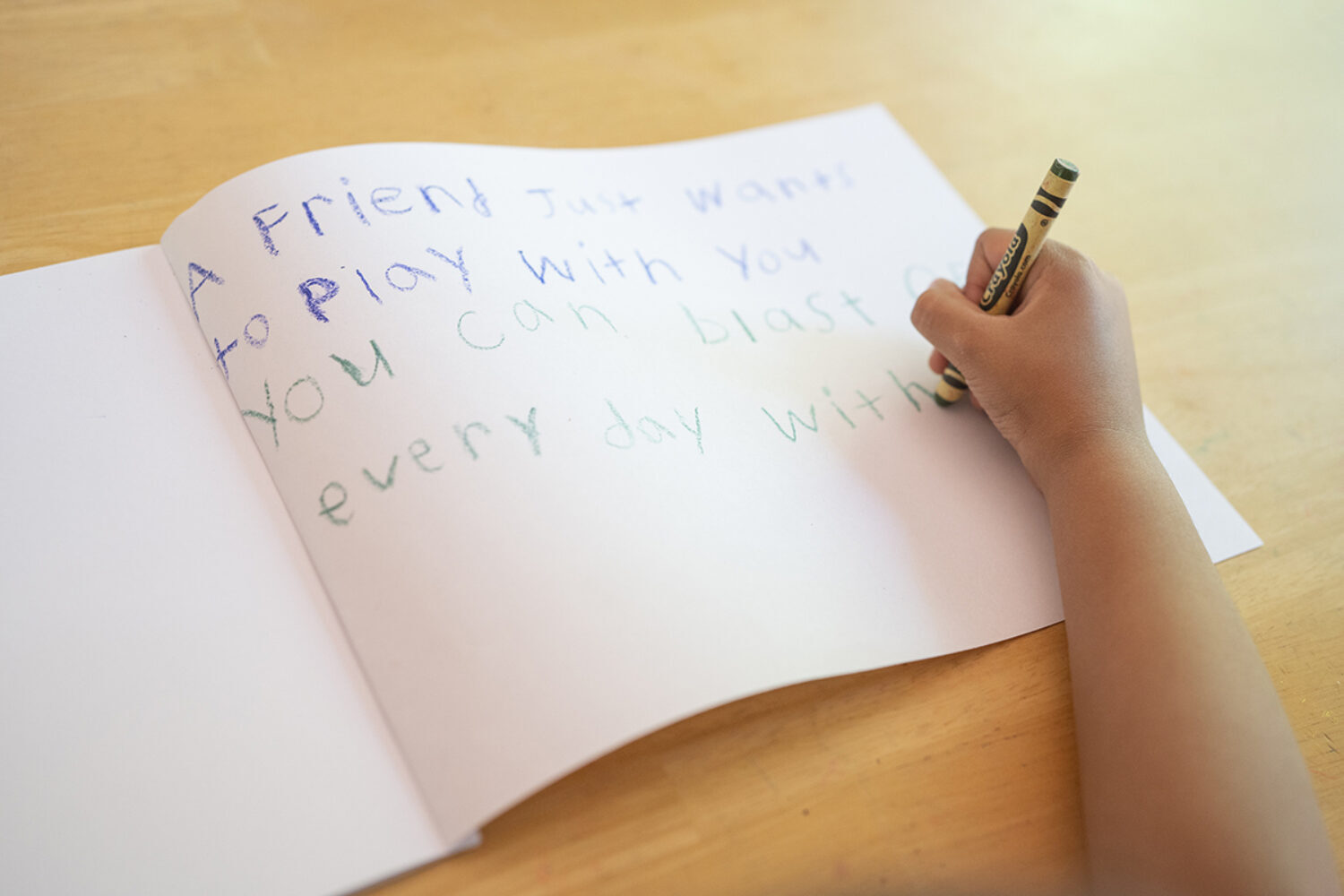 Child writing in a blank workbook.