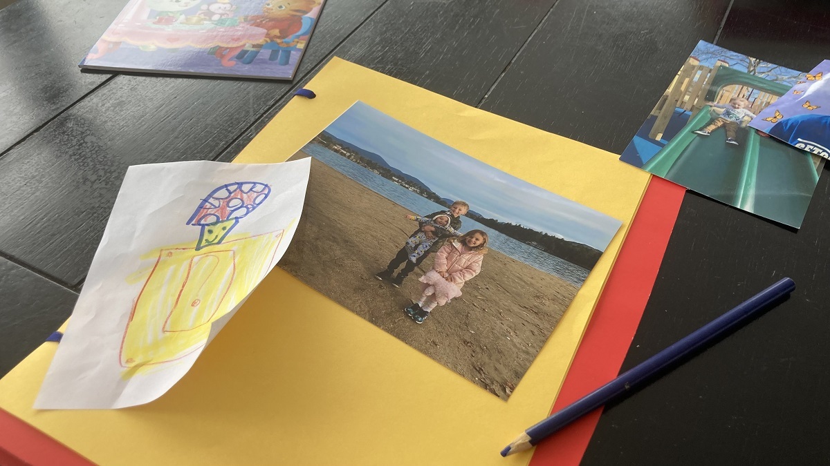 Image of memory book making supplies including construction paper, a pencil, and photographs.