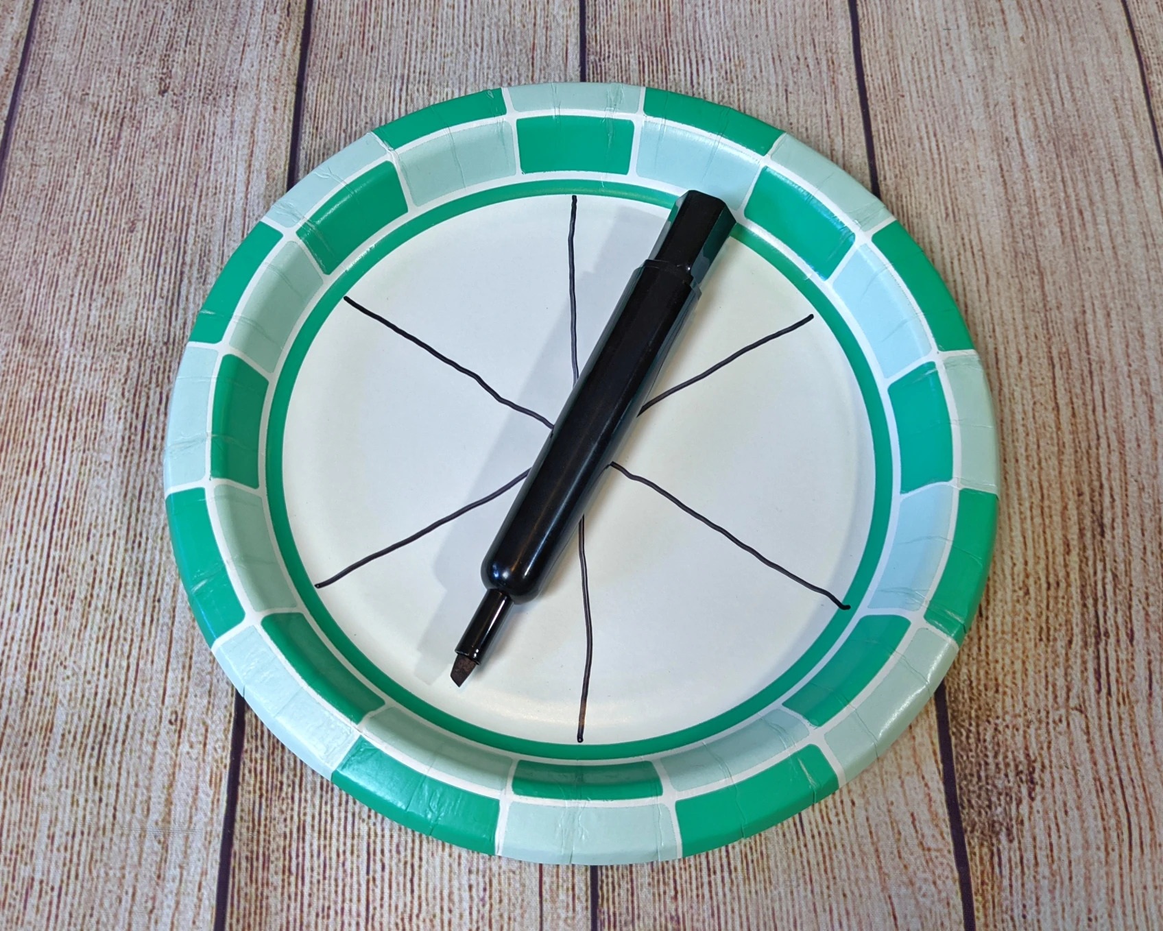 A paper plate split into 6 sections sits on a table with a marker on top.